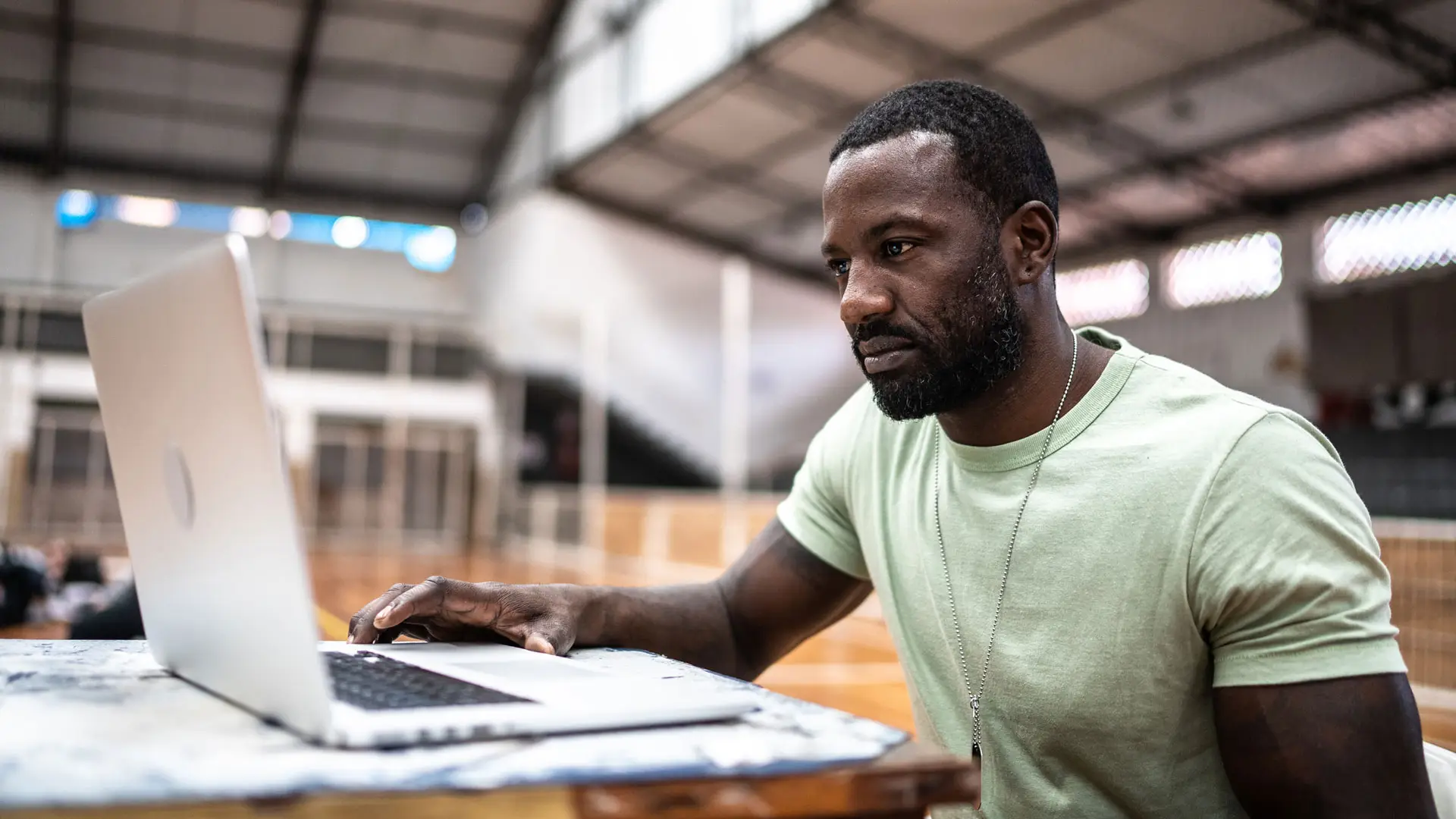 Man sat using laptop in sports hall