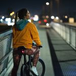 Rear view night shot of a young woman biking in the city street.