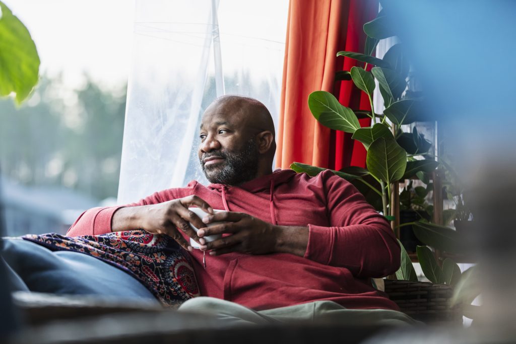 A man relaxes on a sofa, he looks out of a window