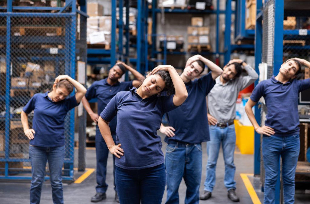 Group of workers stretching in a warehouse