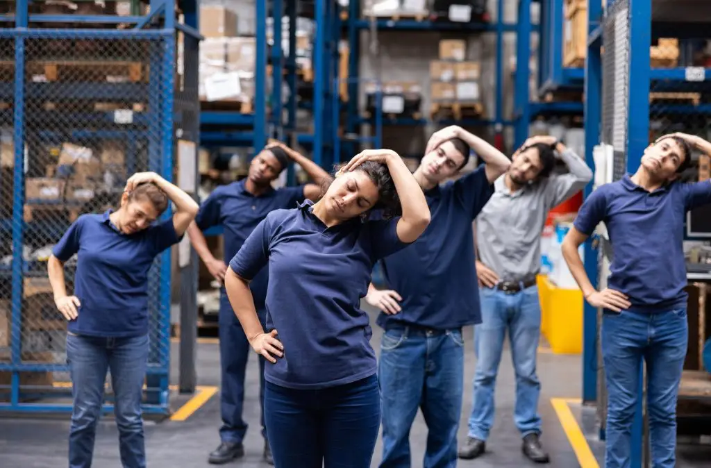 Group of workers stretching in a warehouse