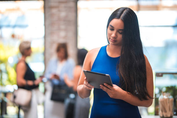 A woman in sportswear looks down at a tablet.