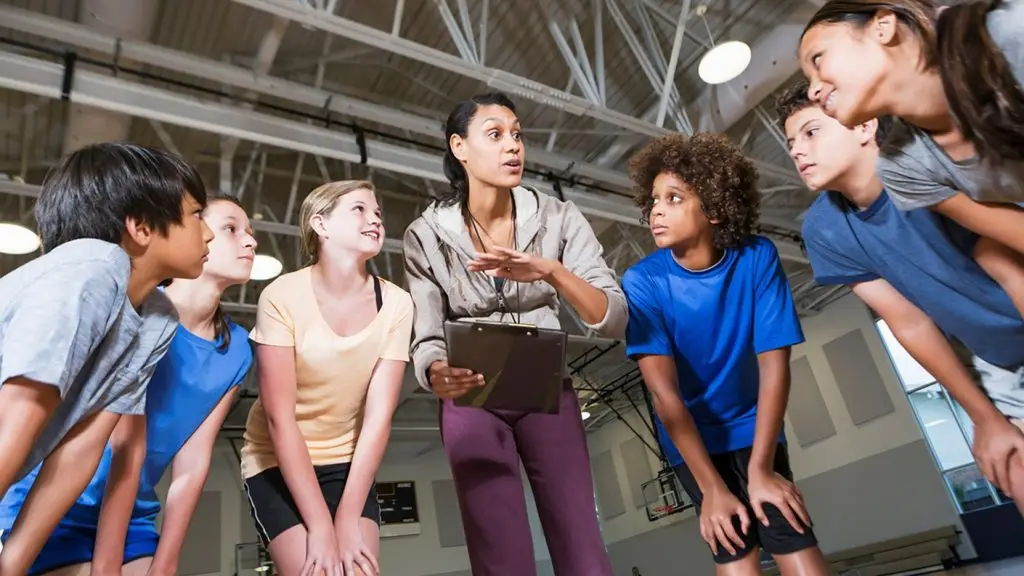 group of children listening to coach with clipboard