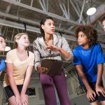group of children listening to coach with clipboard