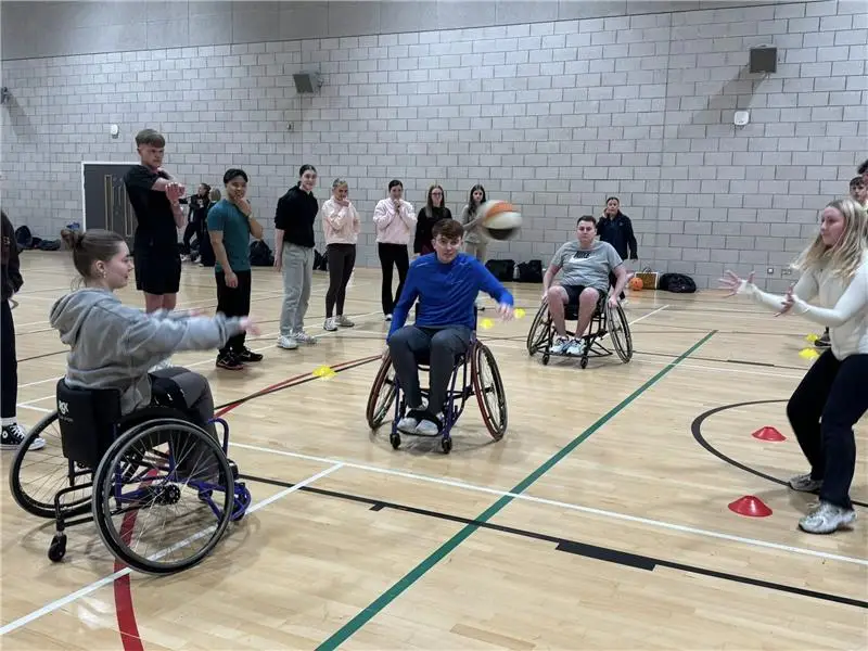 Young people play wheelchair basketball in a sports hall