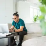 Young man typing on laptop sitting on a sofa