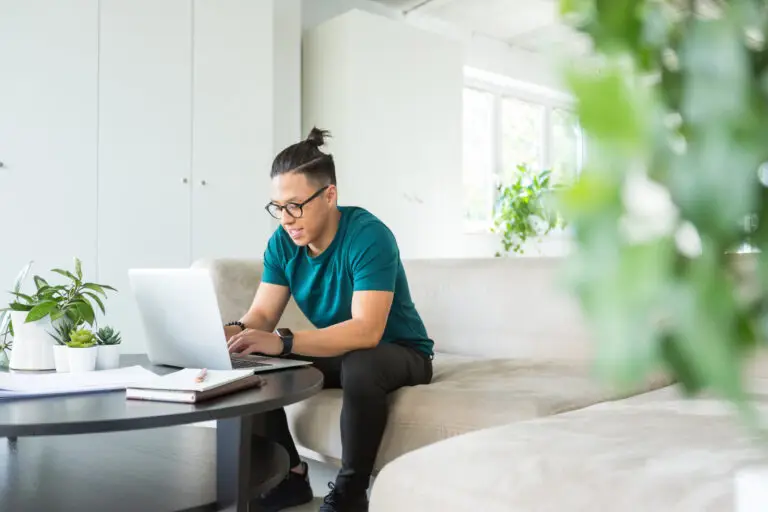 Young man typing on laptop sitting on a sofa
