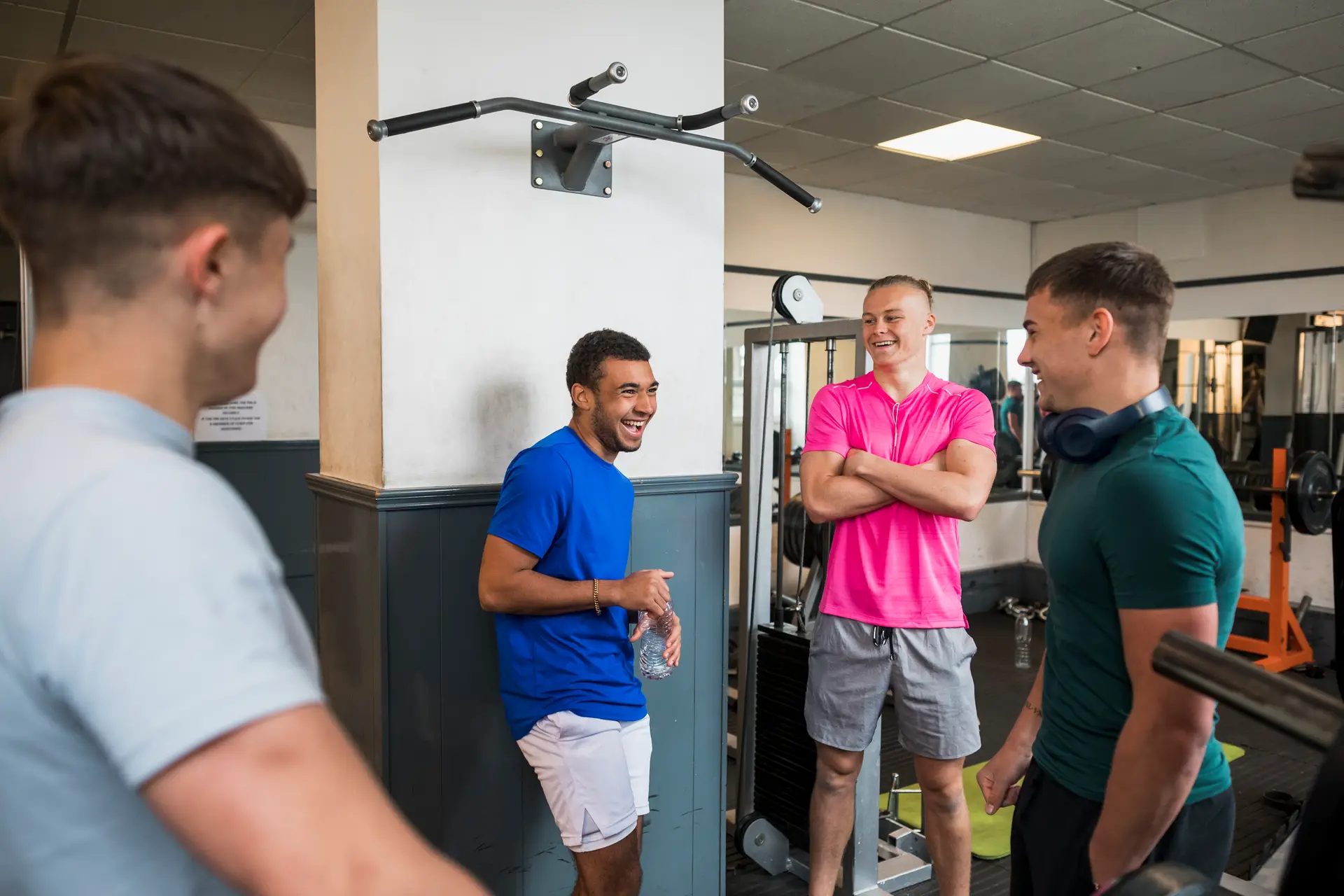 A group of young men stand in a circle chatting at a gym