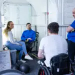 A team of mixed ages have a meeting in a gym office.