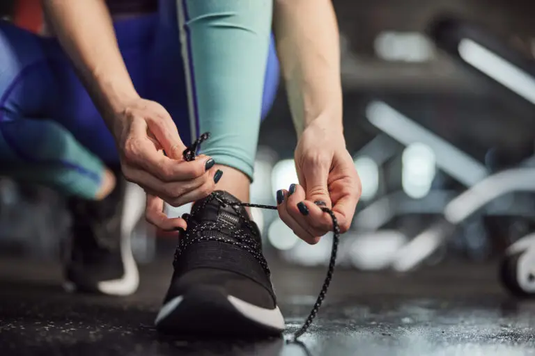 An unseen women ties the lace of her trainer