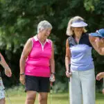 Older women in golfwear stand and chat.