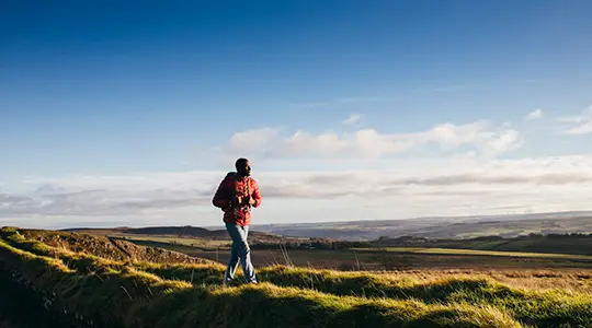 One young adult walking on Hadrian's Wall in Northumberland, UK countryside.