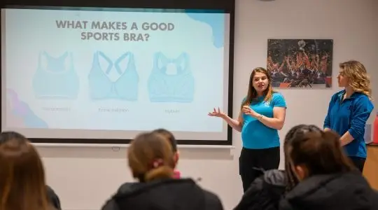 A woman presents a slide about types of sports bras