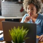 A woman looking at a laptop at a kitchen table