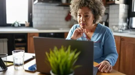 A woman looking at a laptop at a kitchen table