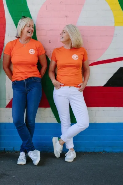 Menopause Movement co-founders Christien and Ann stood against a colourful wall