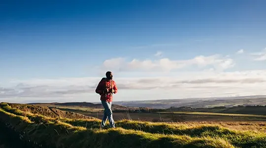 One young adult walking on Hadrian's Wall in Northumberland, UK countryside.