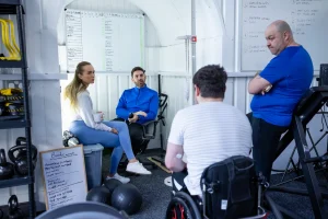 A team of mixed ages have a meeting in a gym office.
