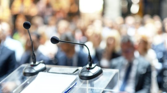 Microphones in focus at business conference, corporate presentation, workshop, coaching training, news conference, company meeting, public or political event. Public speaking concept.